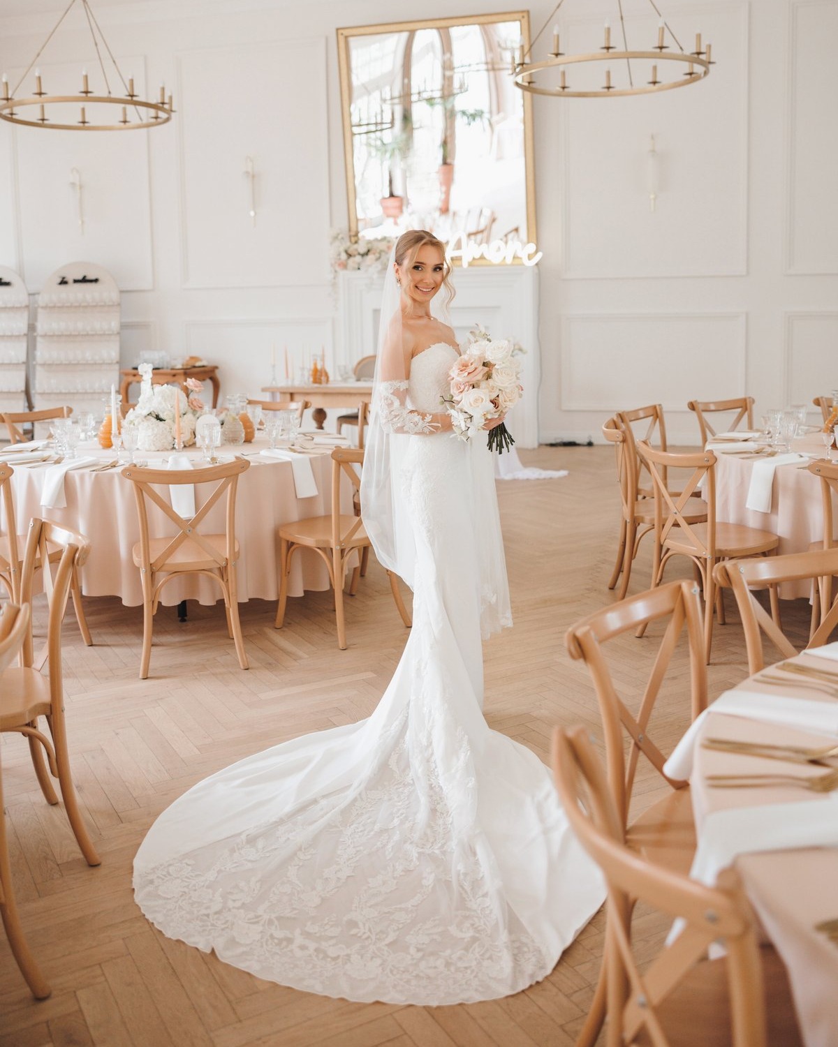 Elegancka panna młoda w koronkowej sukni ślubnej z długim trenem w stylowej sali weselnej
